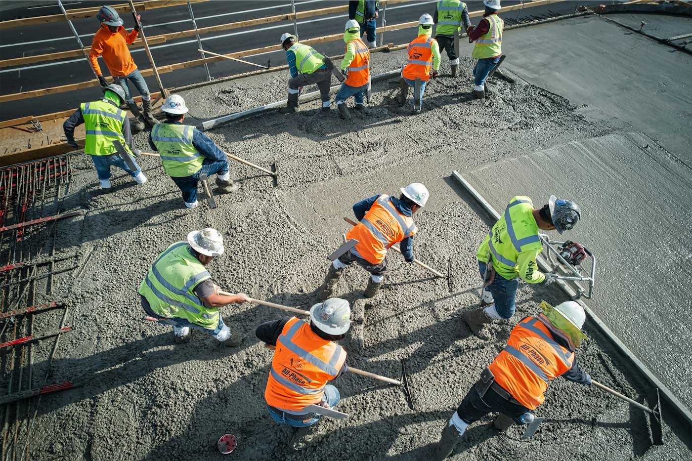 Construction crew in high-visibility gear placing and finishing fresh concrete